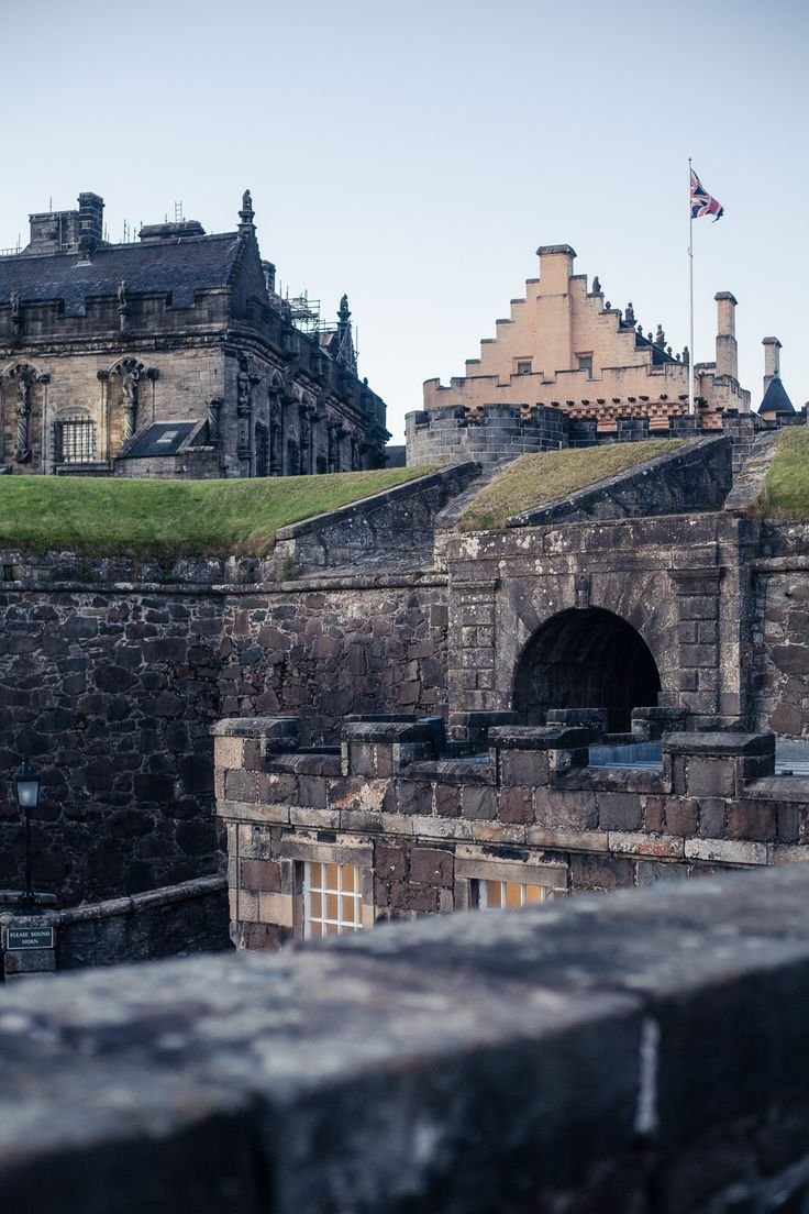 This may contain: an old castle with a flag flying on top of it's roof and some buildings in the background