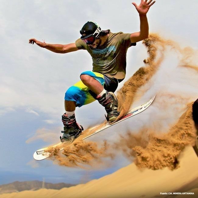 This may contain: a man riding a snowboard down the side of a sand dune covered in dirt
