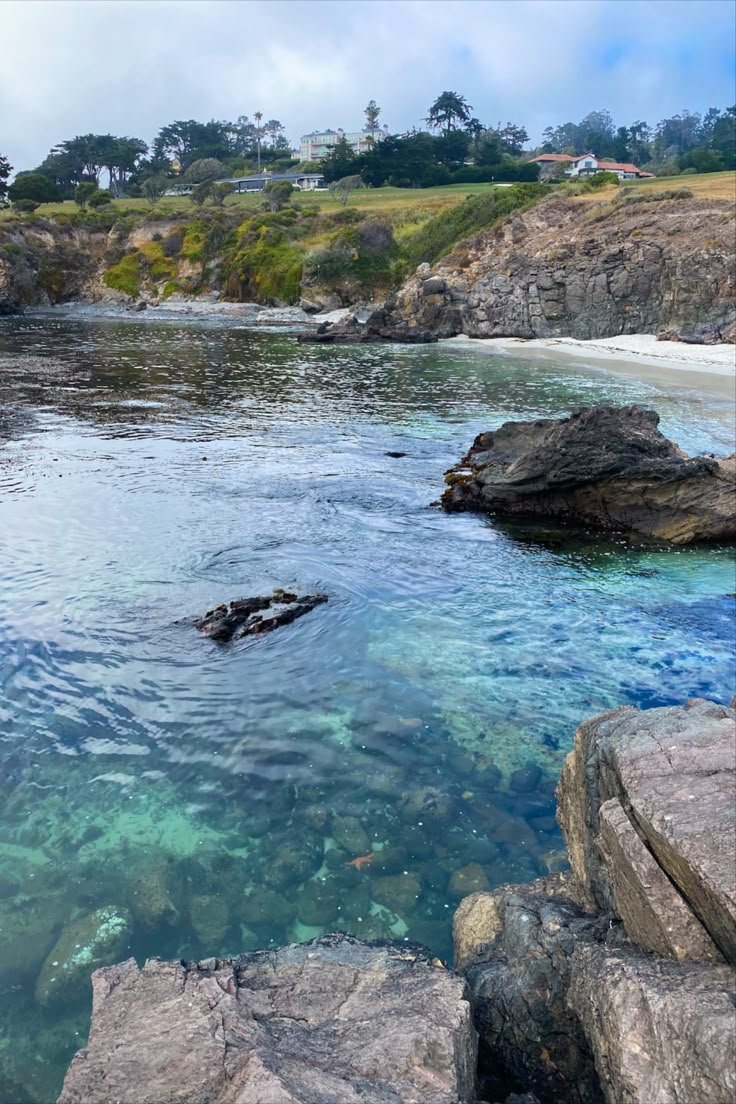 This may contain: a body of water surrounded by large rocks