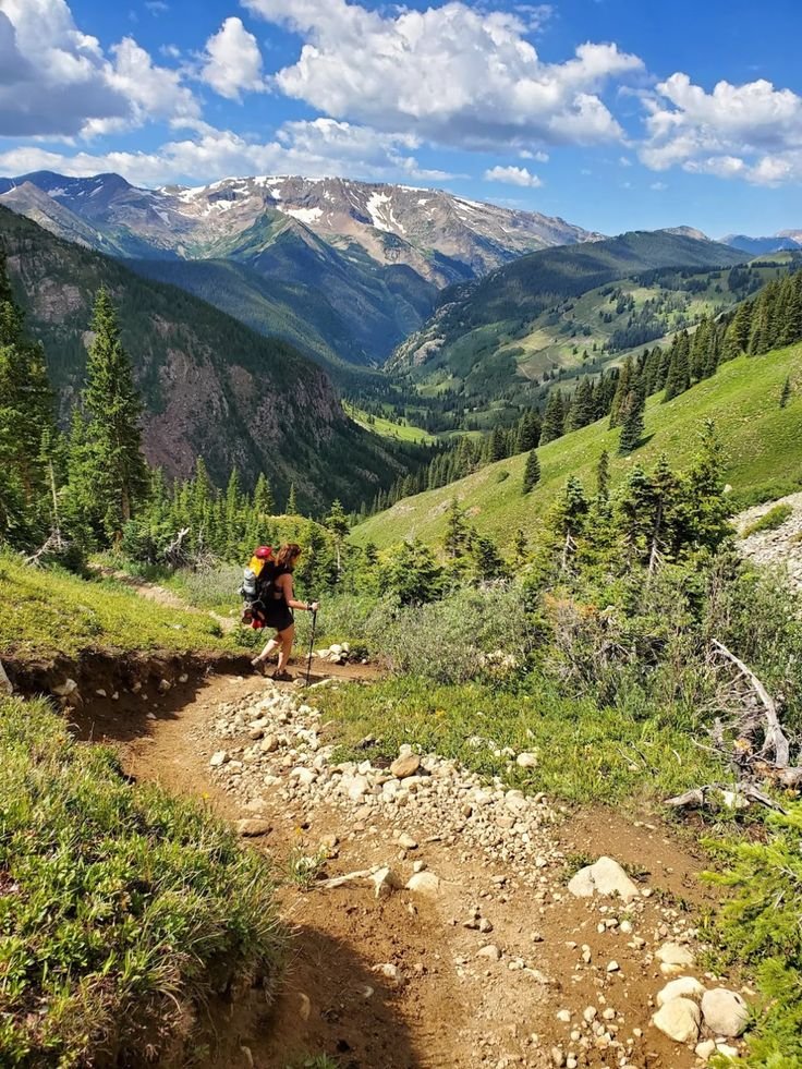This may contain: a person hiking up a trail in the mountains