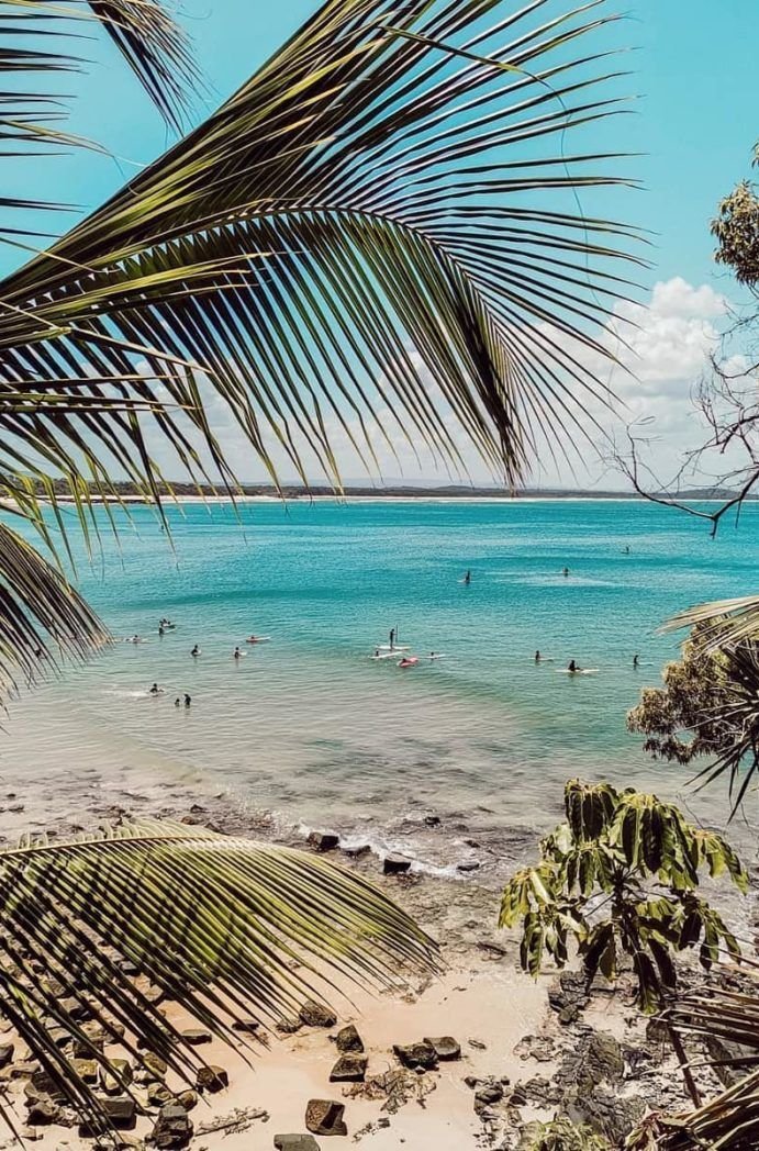 This may contain: people are swimming in the ocean near palm trees