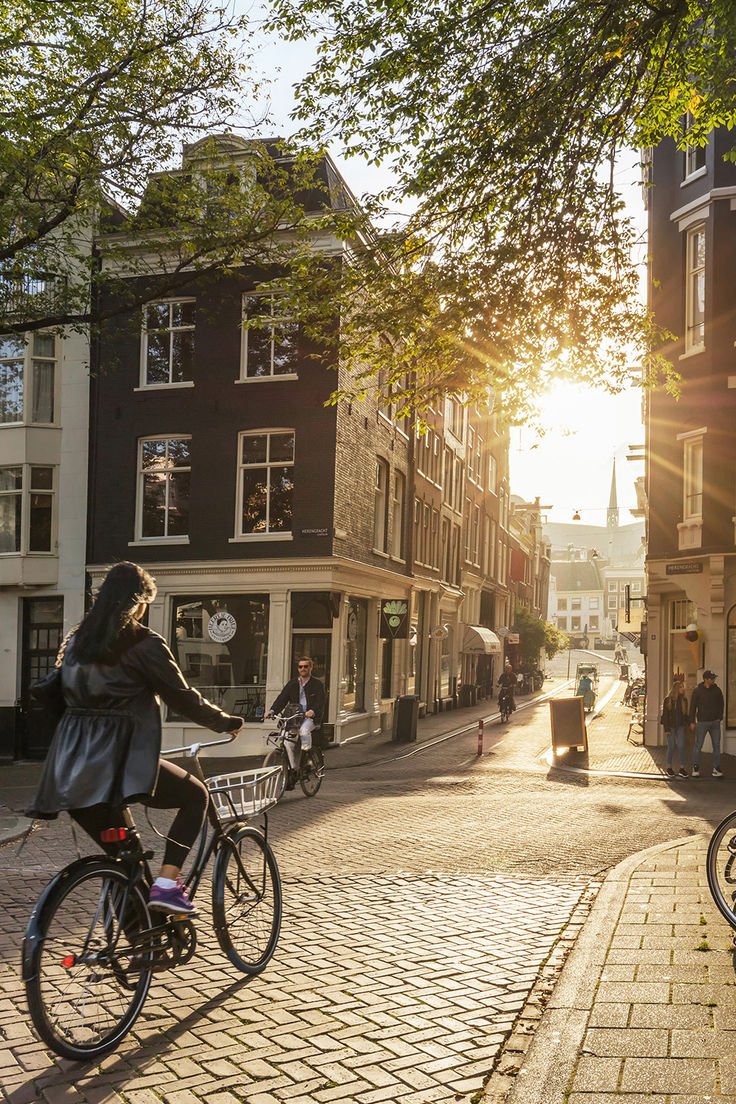 This may contain: the woman is riding her bike down the cobblestone street in the town center