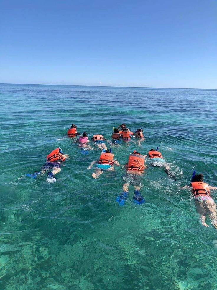 This may contain: several people swimming in the ocean with life vests on