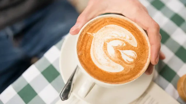 Man's hand holding a cup of coffee on National Cappuccino Day