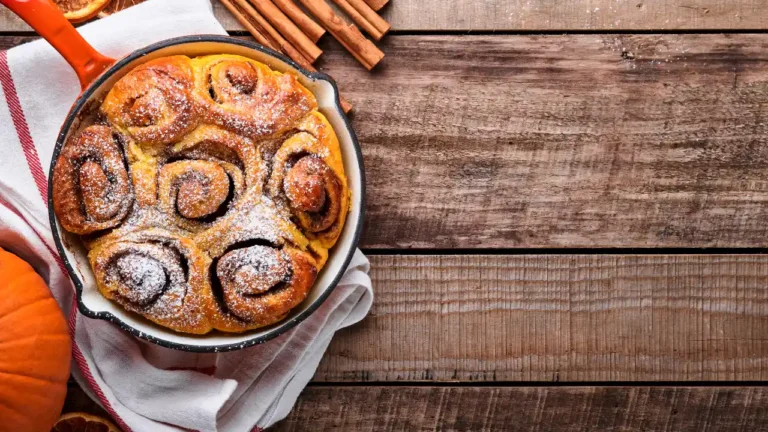 Delicious Cinnabon cinnamon rolls topped with pumpkin, nut, caramel, and sugar cream icing on a rustic wooden background