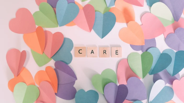 Colorful hearts on a table with letter blocks spelling 'care,' symbolizing love and National I Care About You Day
