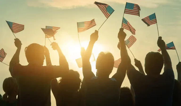 Silhouettes of people holding the USA flag for National Immigrants Day