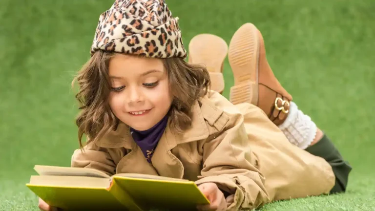 Stylish kid reading a book on green grass for National Children's Book Day.