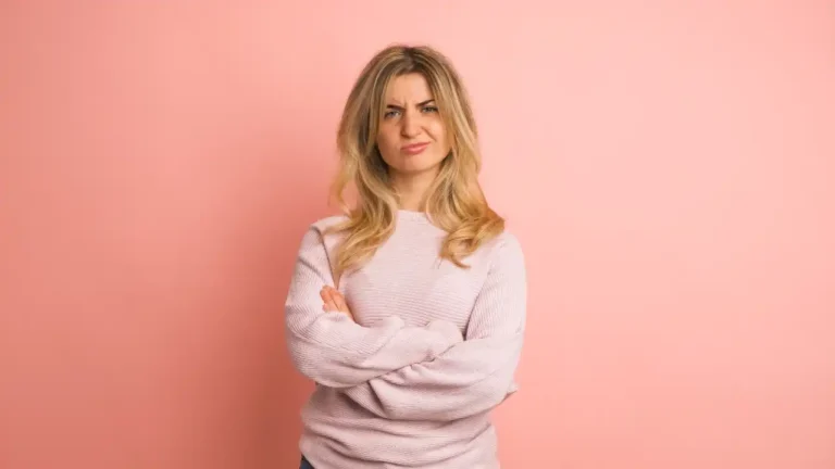 Woman expressing negativity in a pink studio for National Erase Self-Negativity Day