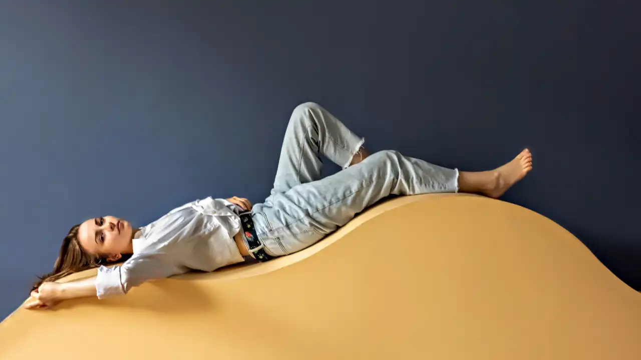 Young woman lying on a wave-shaped chaise lounge for National Lying Day.