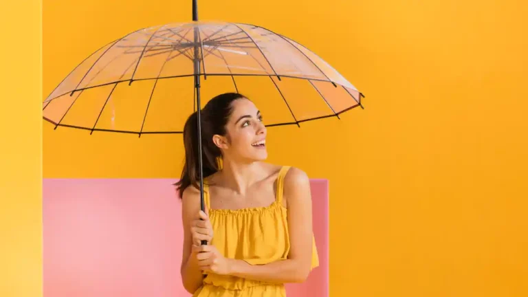 Happy woman in yellow dress holding an umbrella indoors for National Open An Umbrella Indoors Day.