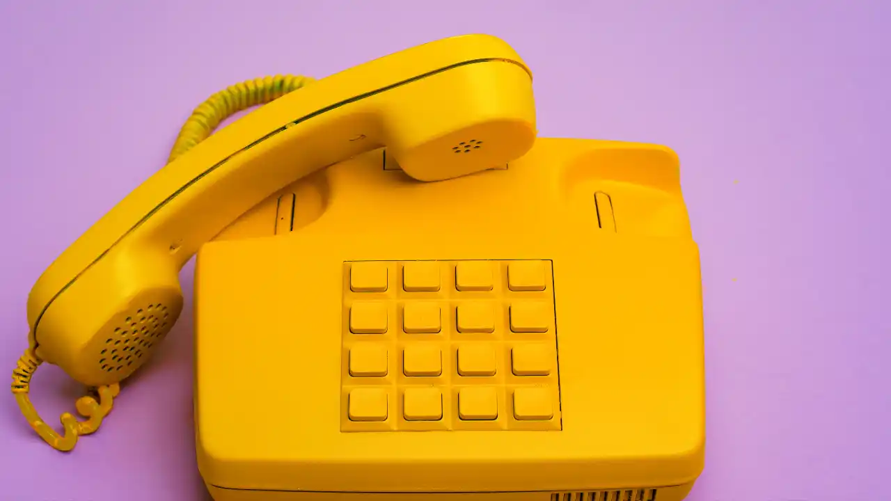 Yellow landline telephone on purple background for National SI 5 Star Phone Certification Day.