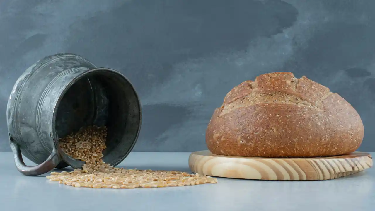 Rye bread roll on wooden board with mug of barley - National Sourdough Bread Day