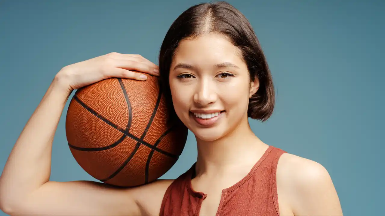 Smiling woman playing basketball for National Student-Athlete Day.