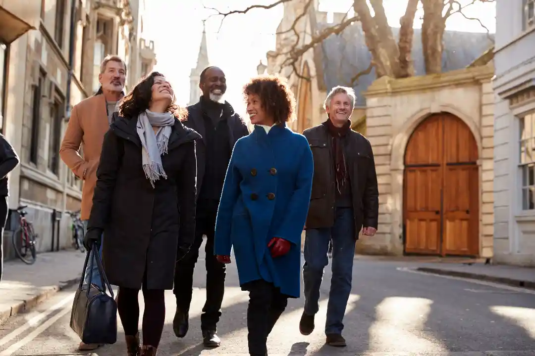 Group of mature friends walking through city streets in fall, celebrating National Walk Around Things Day.