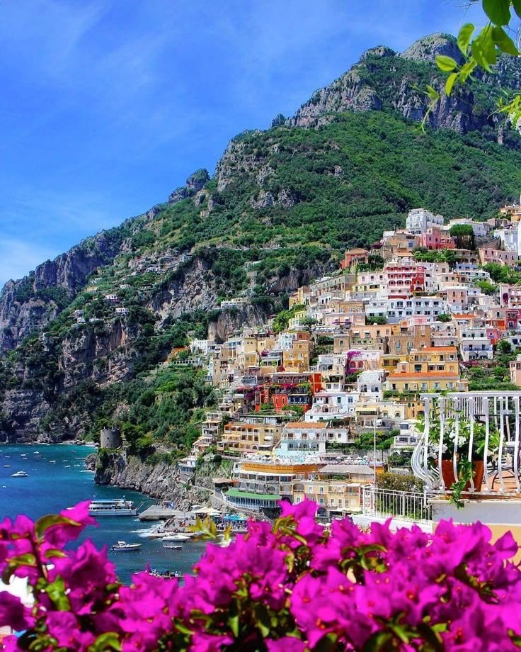 This may contain: the town is perched on top of a hill overlooking the ocean and flowers in bloom