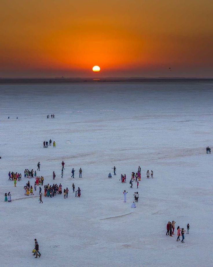 This may contain: a large group of people standing on top of a snow covered field next to the sun