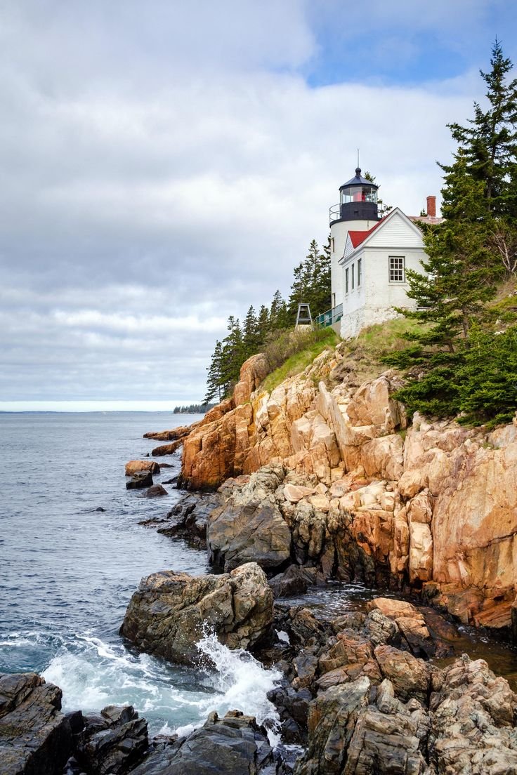 This may contain: a lighthouse on top of a rocky cliff next to the ocean