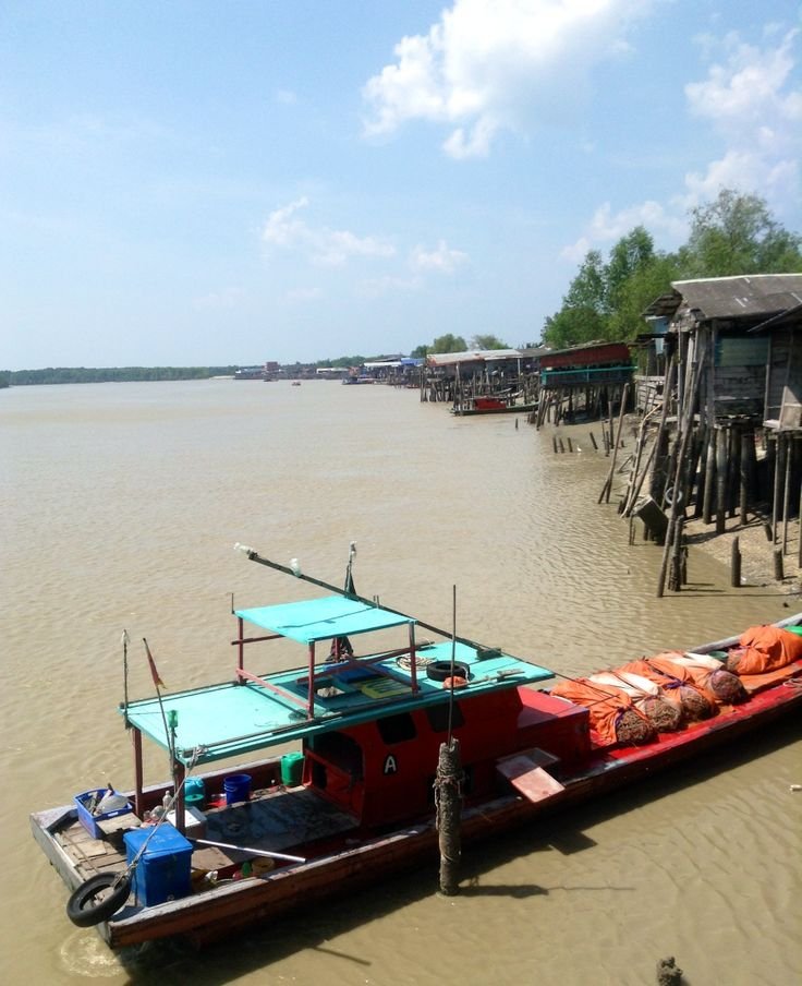 This may contain: a long boat is sitting in the water near some shacks on stilfets