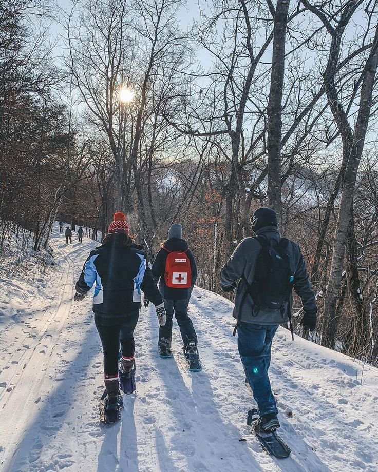 This may contain: three people walking up a snowy hill on skis