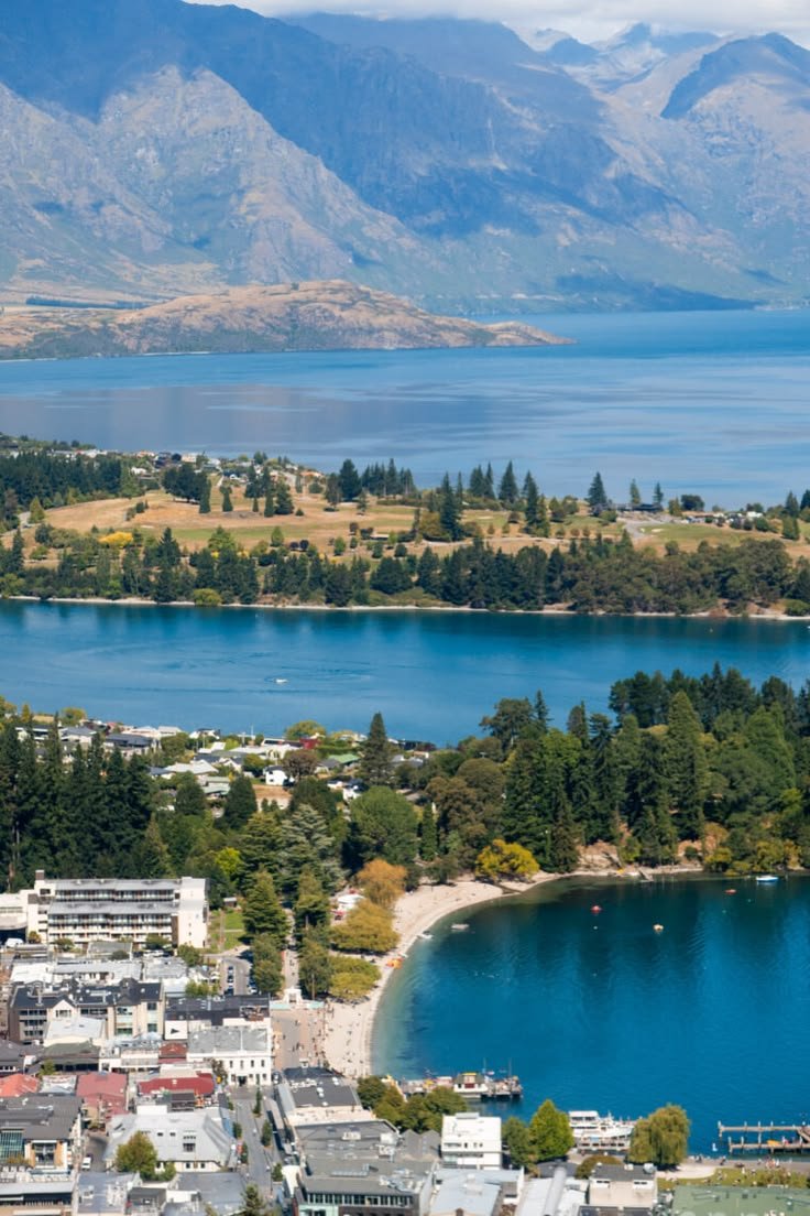 This may contain: an aerial view of a city with mountains in the background and water on the other side