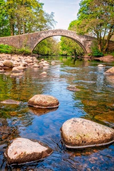 This may contain: a stone bridge over a river with rocks in the water