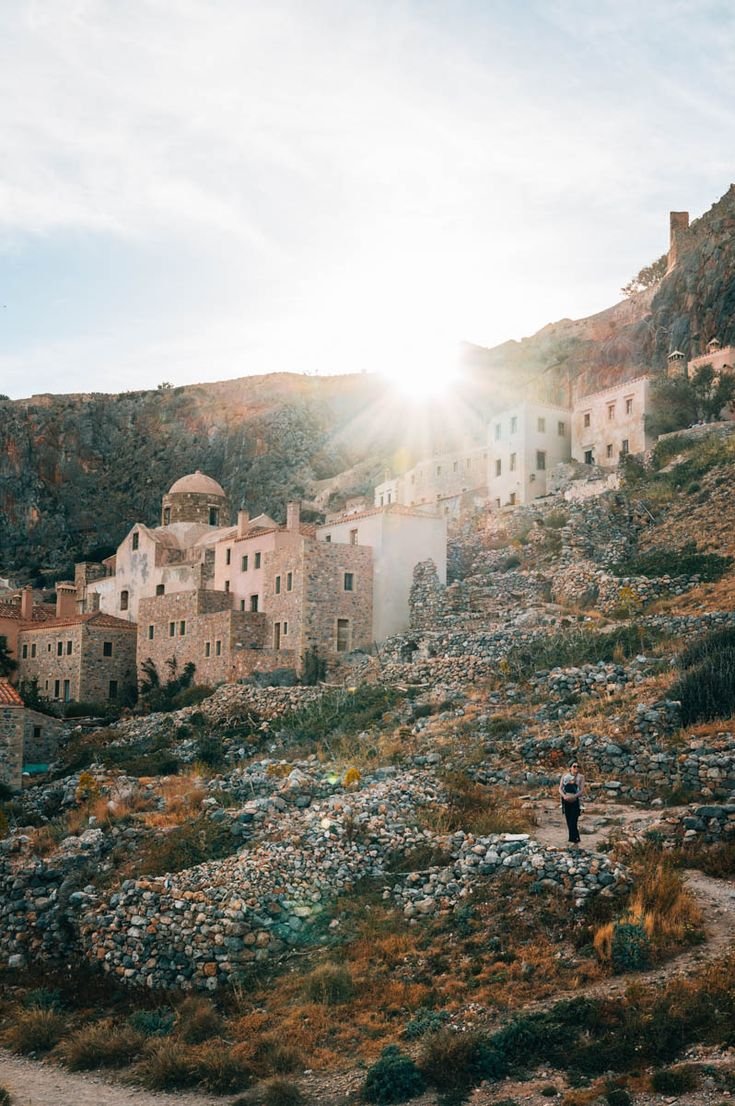 This may contain: the sun shines brightly over an old village on top of a rocky hill, surrounded by greenery