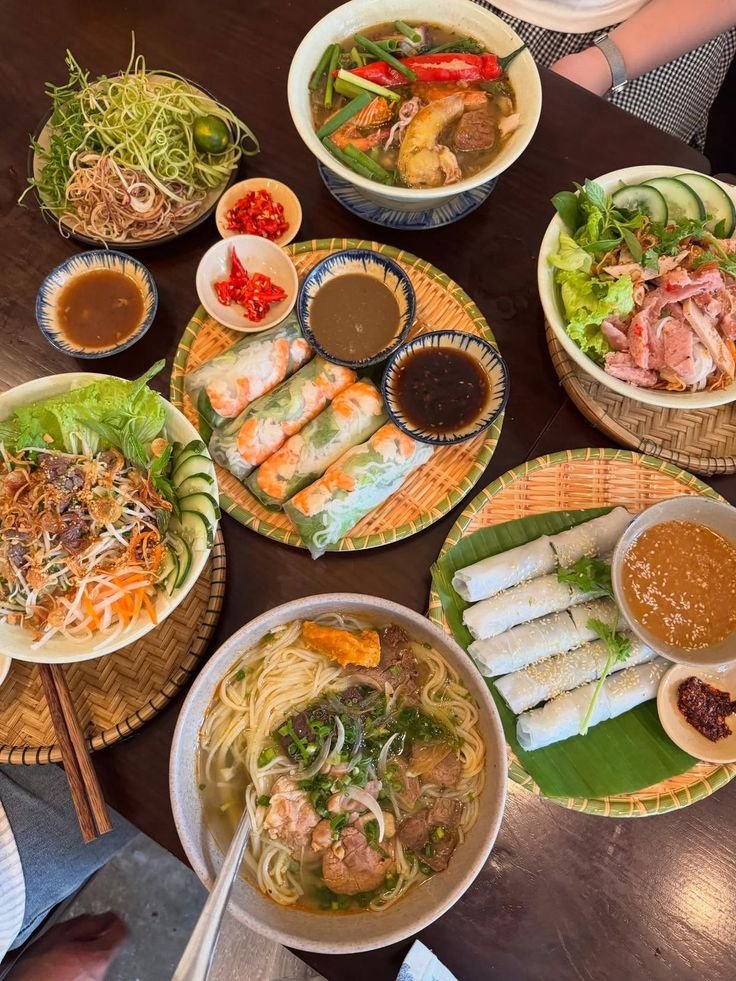This may contain: a table topped with plates of food next to bowls of soup and dipping sauces
