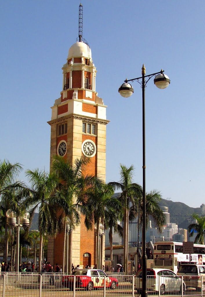 This may contain: a tall clock tower sitting in the middle of a park with palm trees around it