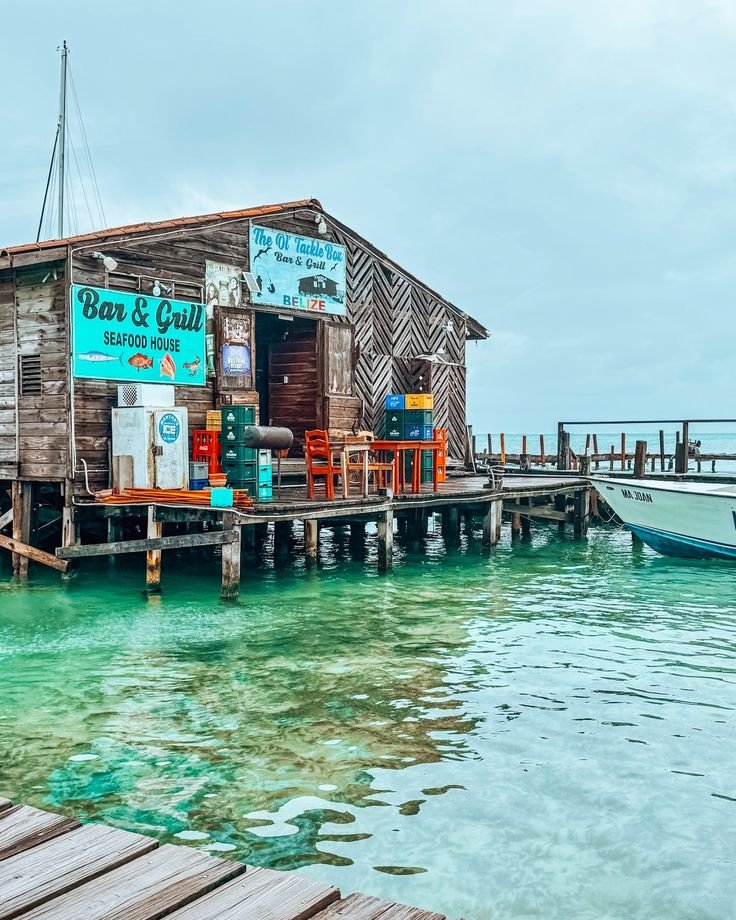 This may contain: a boat is docked next to a small wooden shack on the water's edge