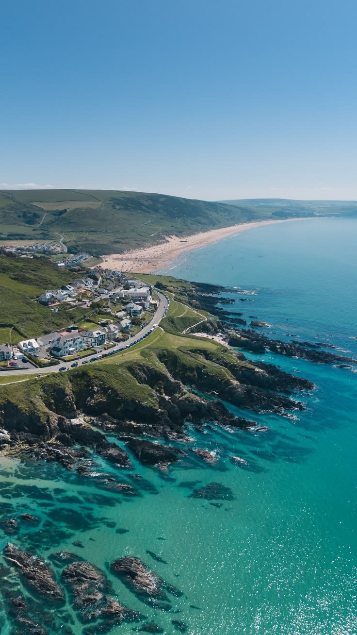 This may contain: an aerial view of the ocean and coastline with houses in the foreground, along with rocky shoreline