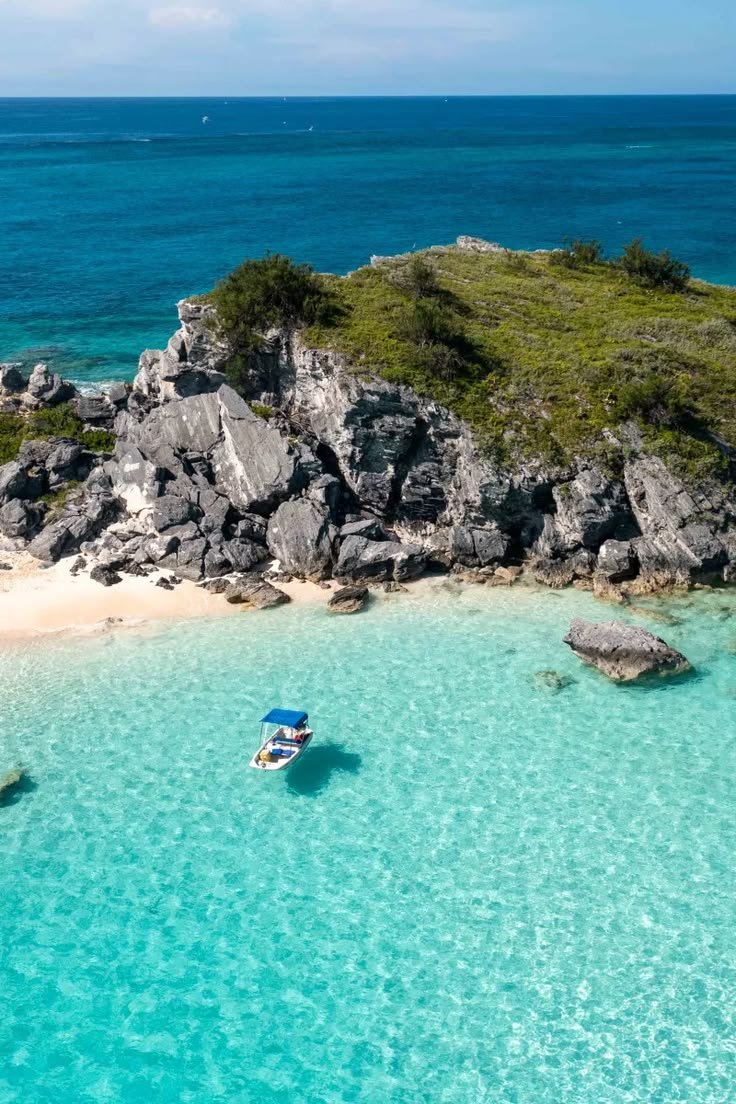 This may contain: an aerial view of a beach with boats in the clear blue water and rocky shoreline