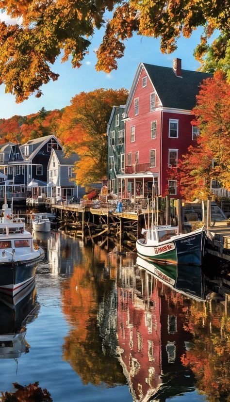 This may contain: boats are docked at the dock in front of houses with autumn foliage around them and trees lining the water