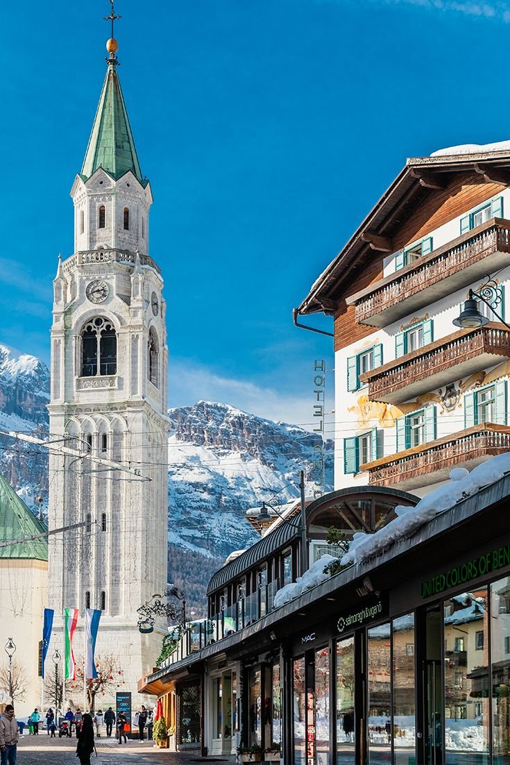This may contain: people walking down the street in front of a building with a steeple on top
