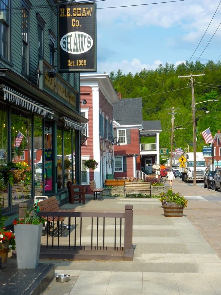 This may contain: an empty street with shops and parked cars