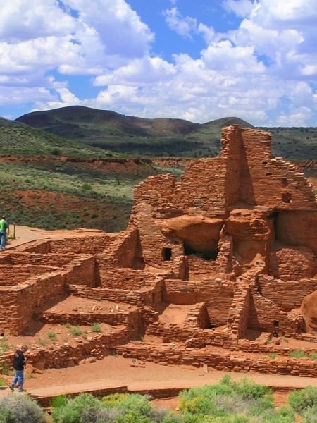 This may contain: two people standing in front of an old pueblo