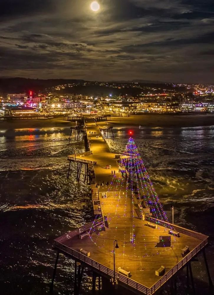 This may contain: the pier is lit up with christmas lights