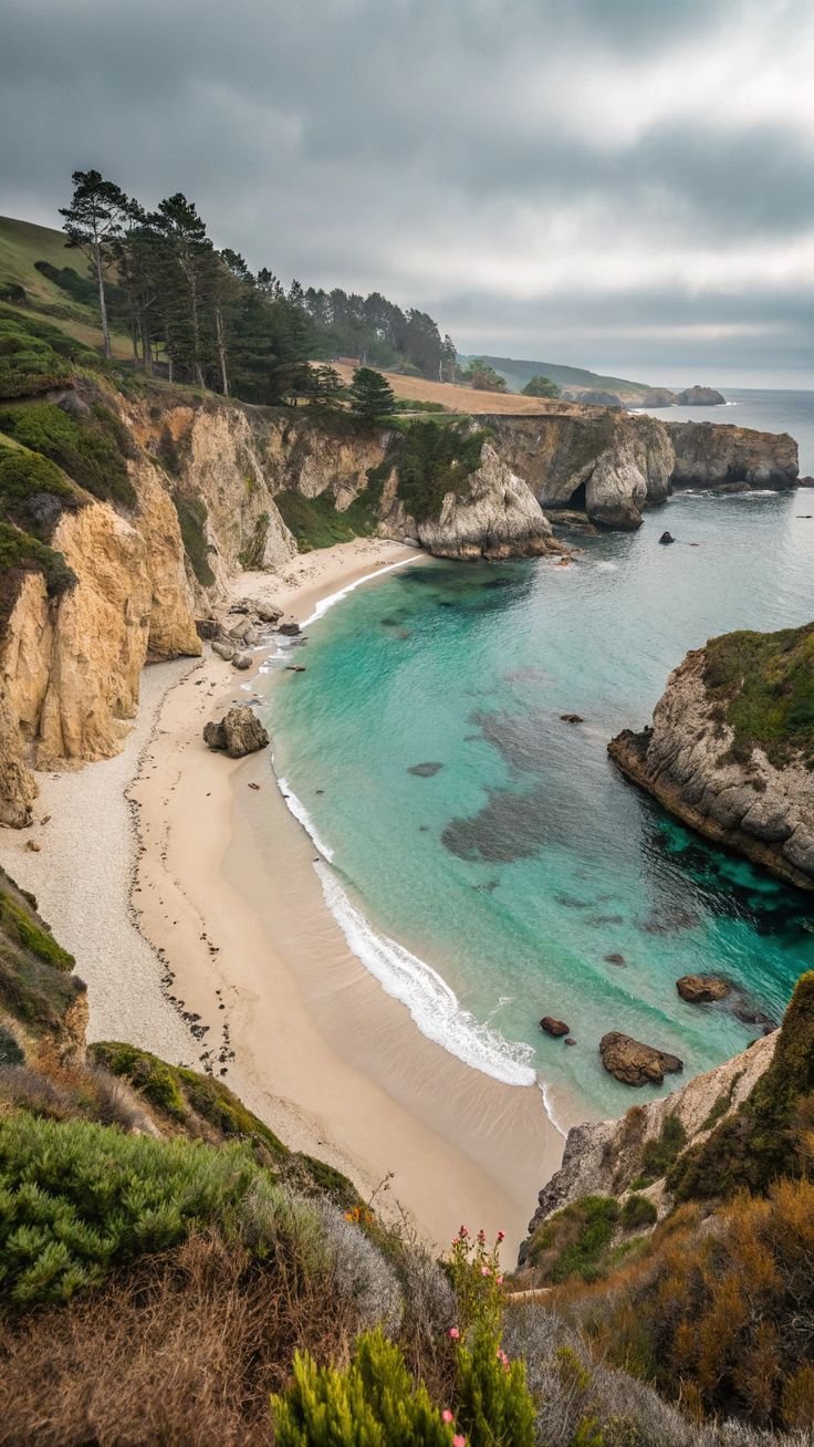 This may contain: the beach is surrounded by rocky cliffs and blue water