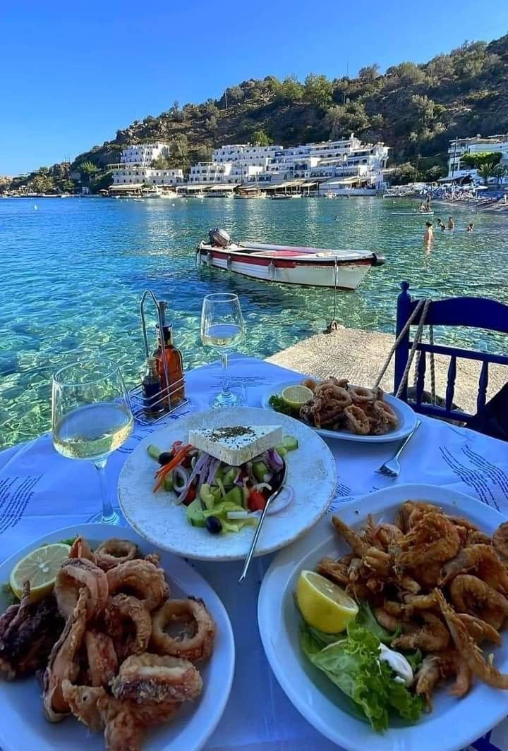 This may contain: plates of food are sitting on a table near the water