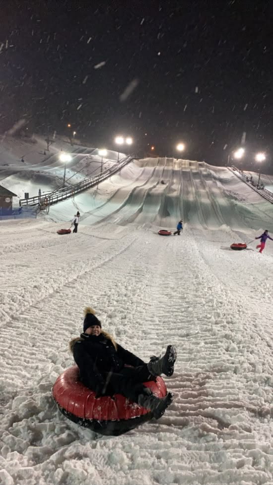 This may contain: a person is sledding down a hill at night with snow falling on the ground
