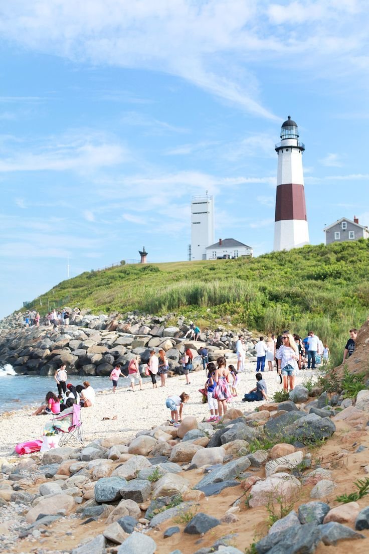 This may contain: many people are walking on the beach near a light house