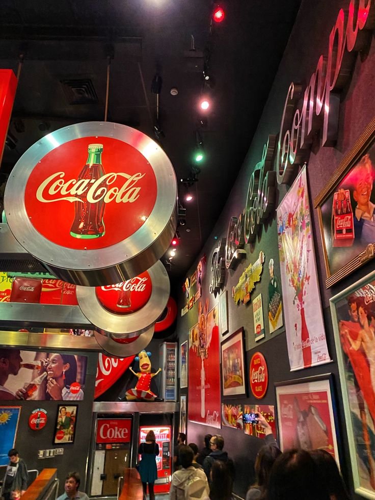 This may contain: the interior of a restaurant with coca - cola signs and advertisements on the wall above it
