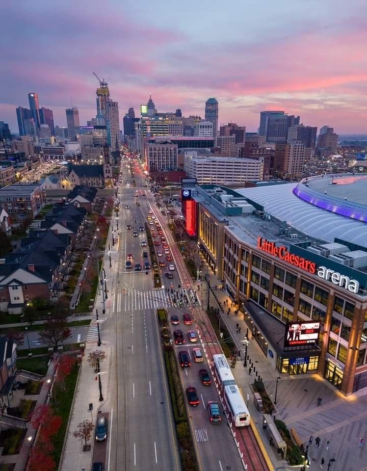 This may contain: an aerial view of a city at dusk with the lights on and cars driving down the street