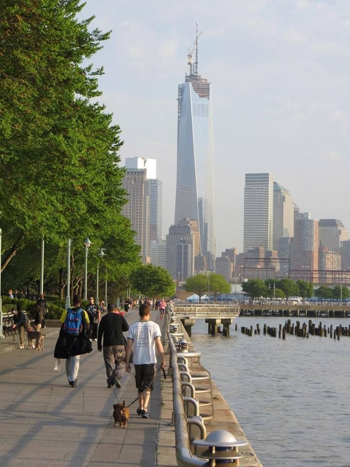 This may contain: people walking along the water with tall buildings in the background