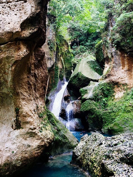This may contain: a small waterfall in the middle of a canyon