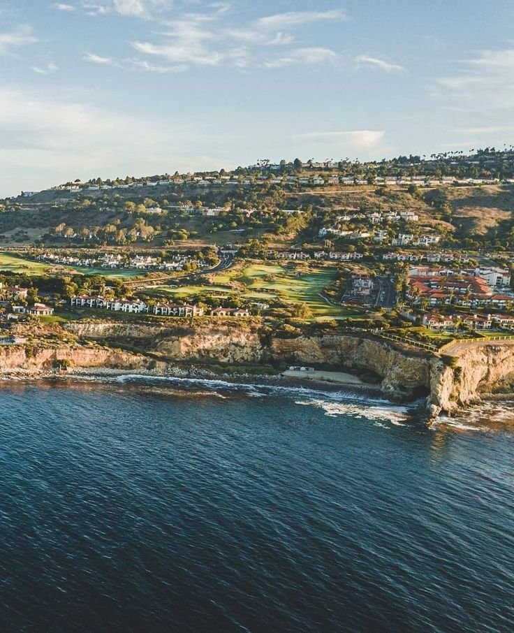 This may contain: an aerial view of the ocean with houses and cliffs in the backgrouds
