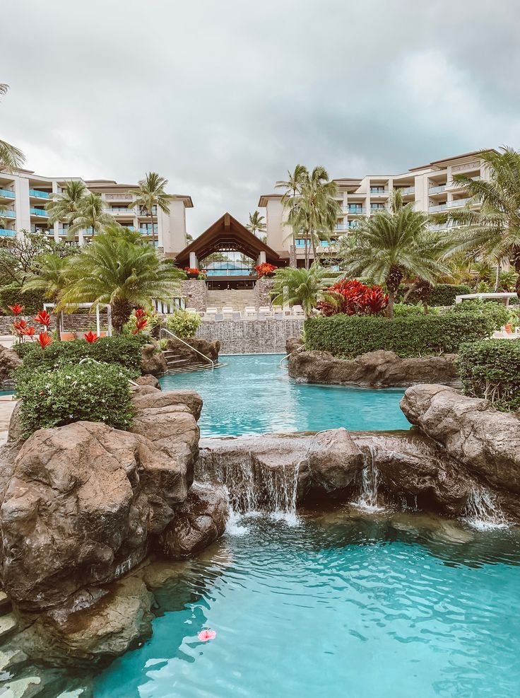 This may contain: an outdoor swimming pool surrounded by palm trees and water features a waterfall that flows into the pool