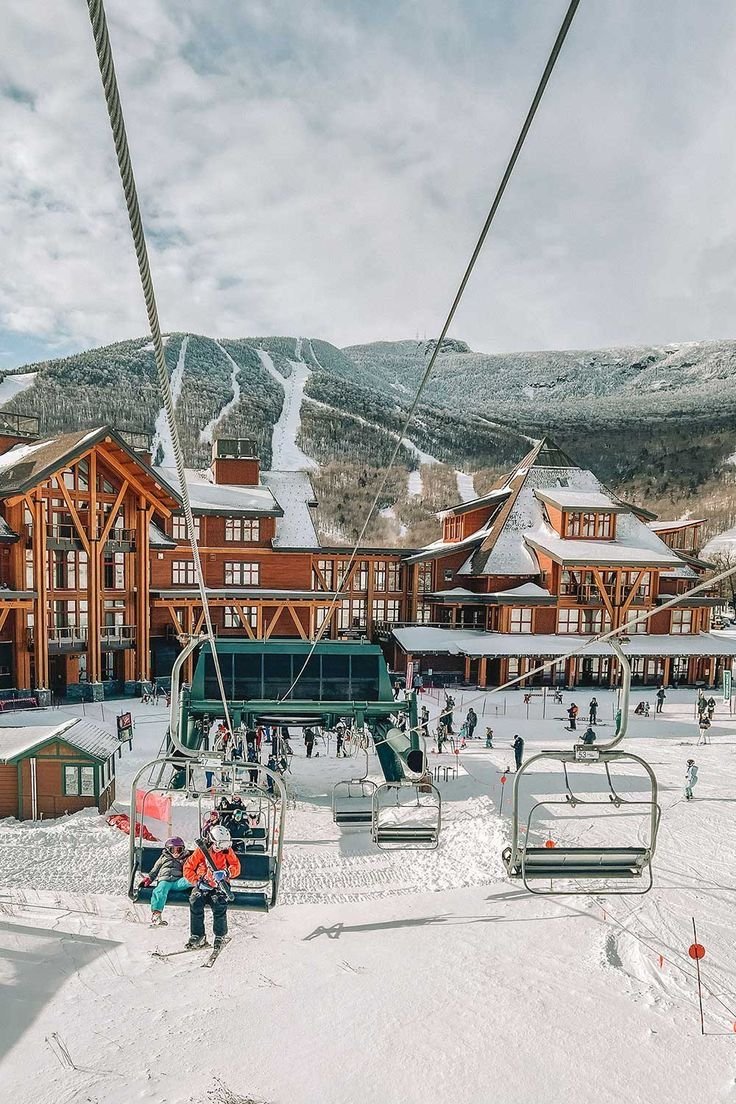 This may contain: skiers and snowboarders at the bottom of a ski lift in front of a resort