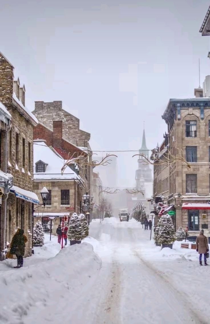 This may contain: a snowy street with people walking on it