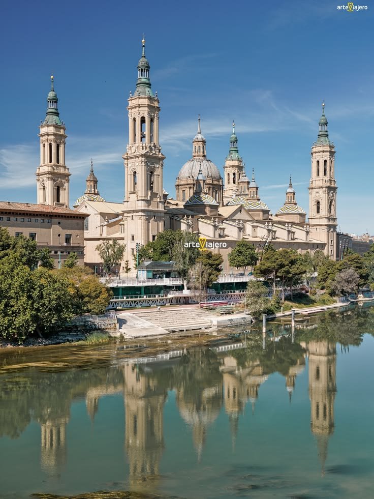 This may contain: a large building with towers on top next to water